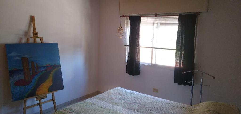 Un dormitorio con una pintura, una cama y una ventana en CORTADA ASTRADA HOME en Rosario
