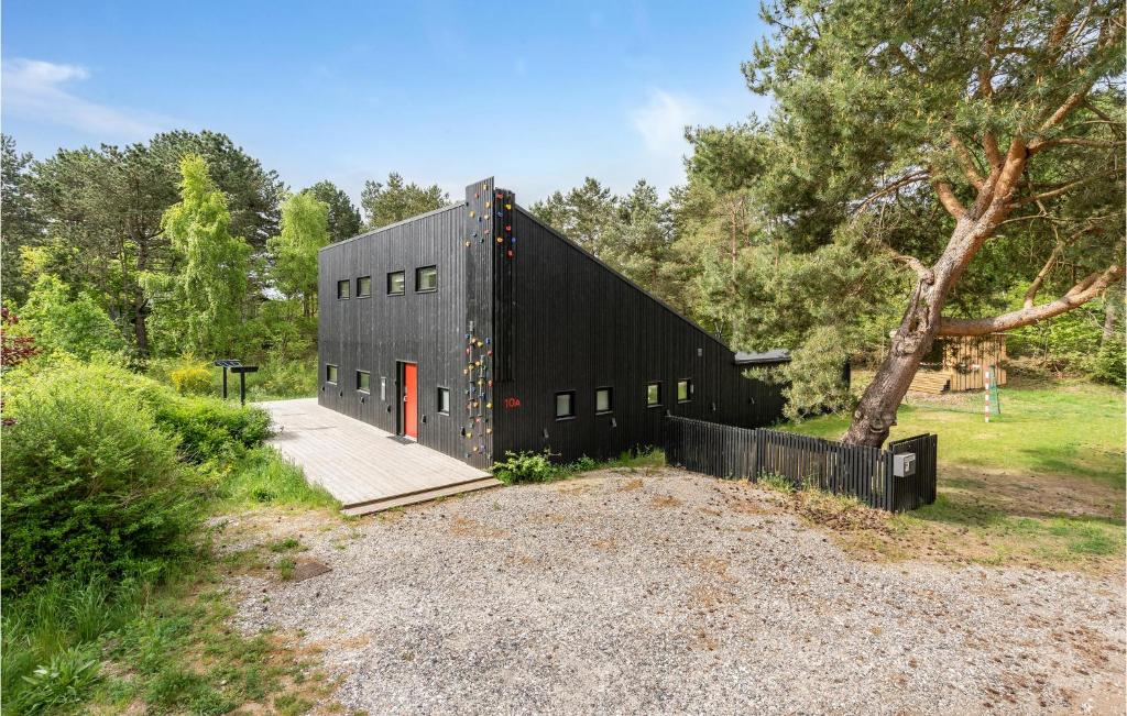 a black building with a red door in a field at 5 Bedroom Awesome Home In Ebeltoft in Ebeltoft