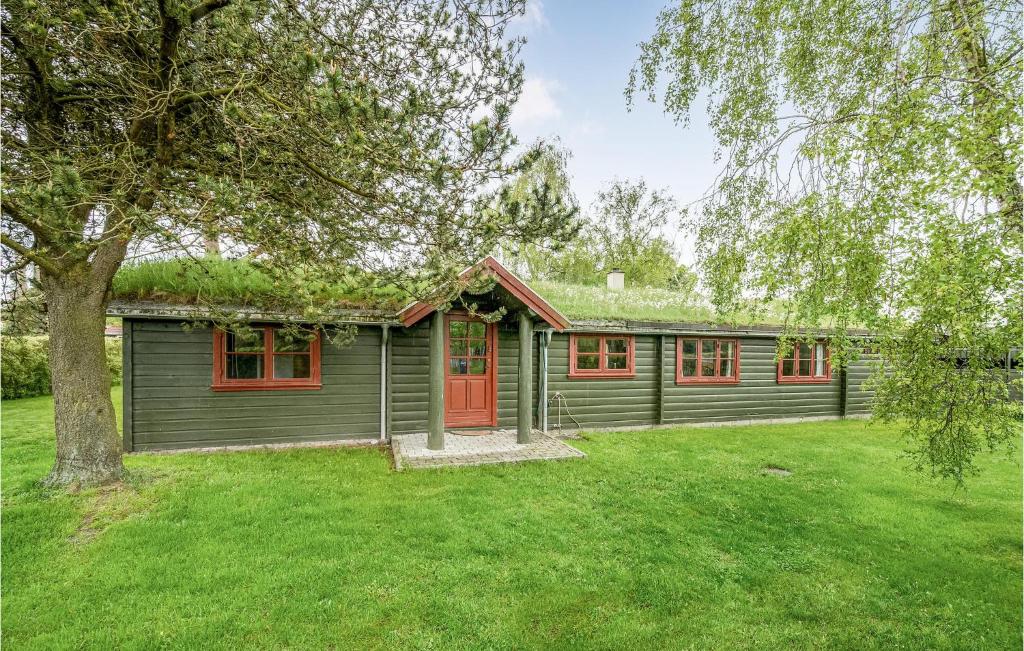 a green house with red windows and a tree at Four-Bedroom Holiday Home In Otterup in Otterup