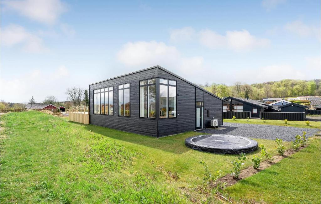a black house with glass windows on a yard at Amazing Home In Sjølund in Sjølund