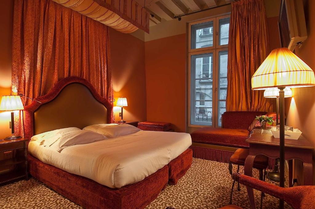 ein Schlafzimmer mit einem Bett, einem Stuhl und einem Fenster in der Unterkunft Hotel Odeon Saint-Germain in Paris