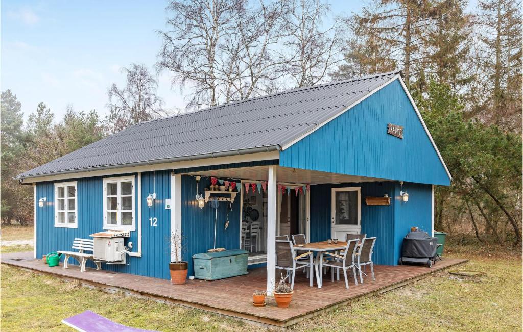 a blue house with a table on a deck at Stunning Home In Aakirkeby With Wifi in Vester Sømarken