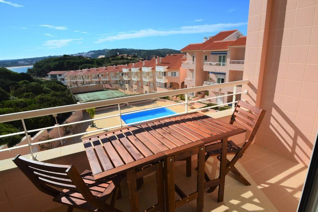 d'un balcon avec une table en bois et une chaise. dans l'établissement Casa da praia - by Smarthomes, à São Martinho do Porto