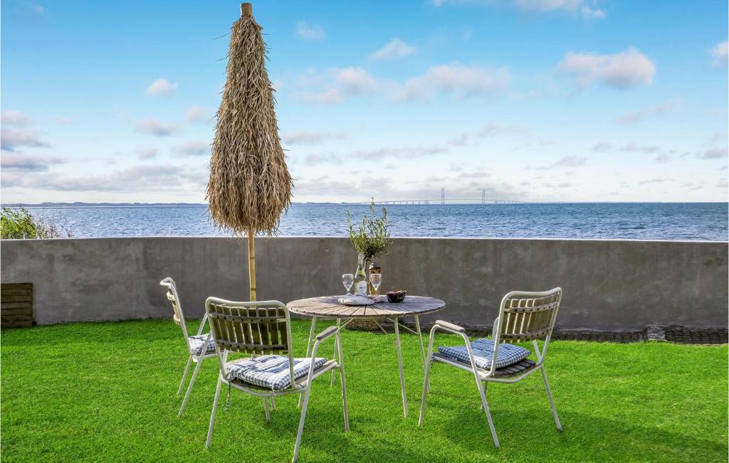 a table and chairs with the ocean in the background at Beach Front Home In Slagelse With Kitchen in Lille Kongsmark