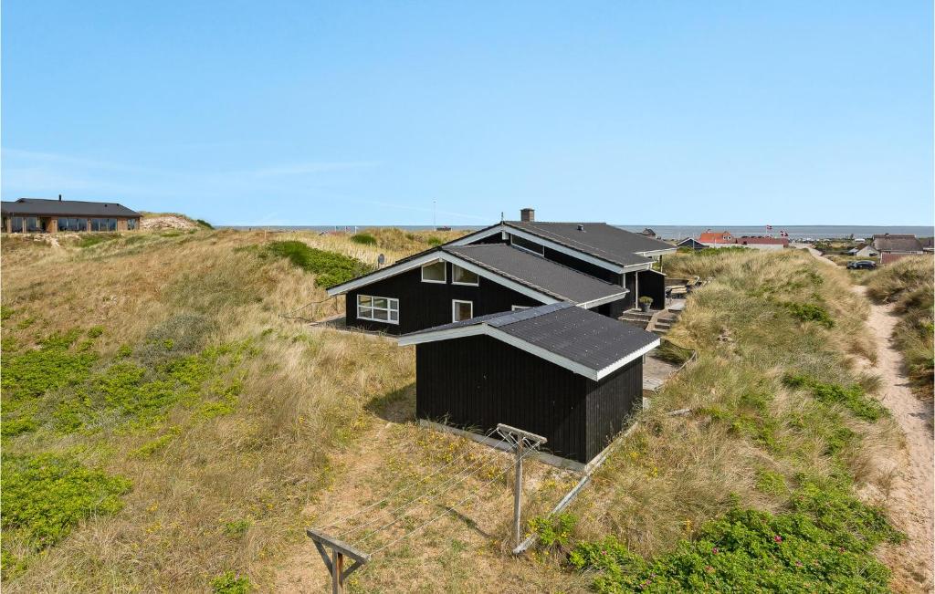 a black house sitting on top of a hill at Amazing Home In Hvide Sande With 4 Bedrooms, Sauna And Wifi in Hvide Sande
