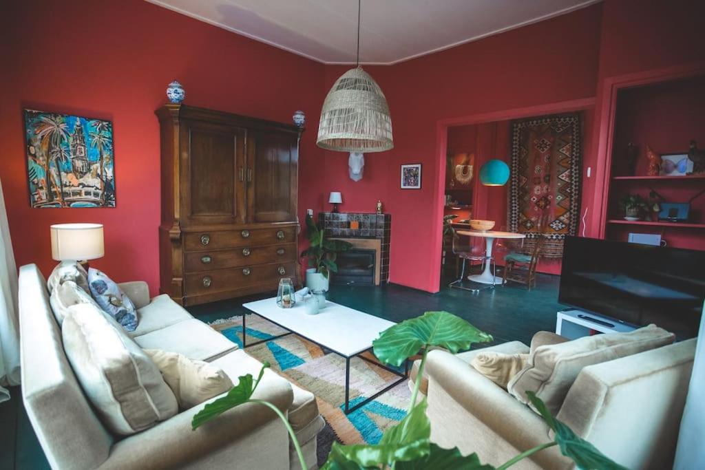 a living room with red walls and two couches at Retreat midden op de Veluwe -ingang Park 1 km in Hoenderloo