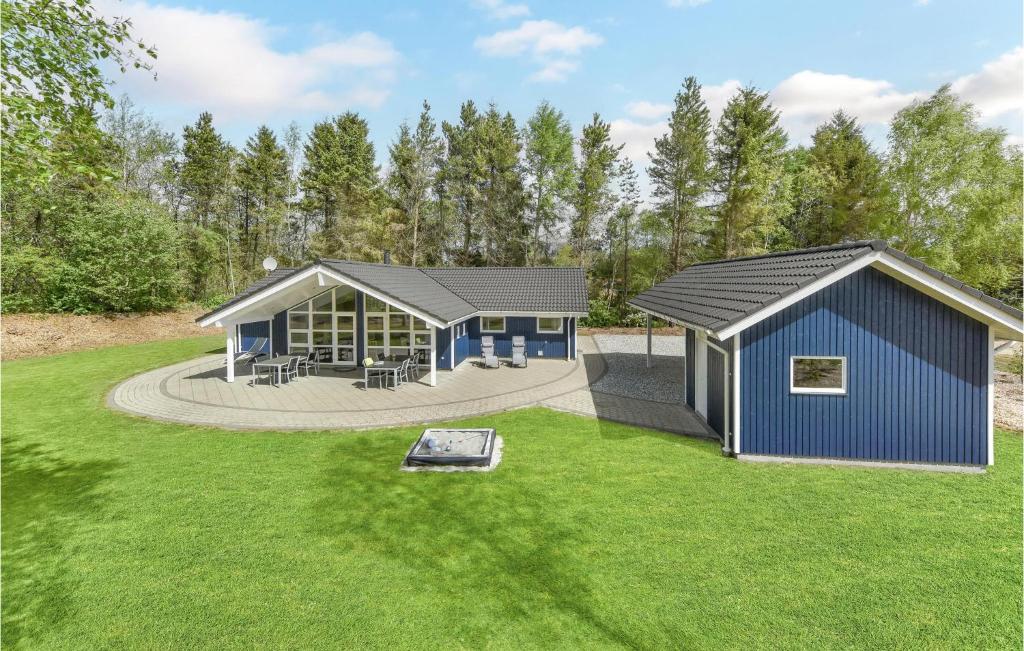 a home with a blue building in a yard at Holiday Home Hybenvangen Oksbøl Denm in Oksbøl