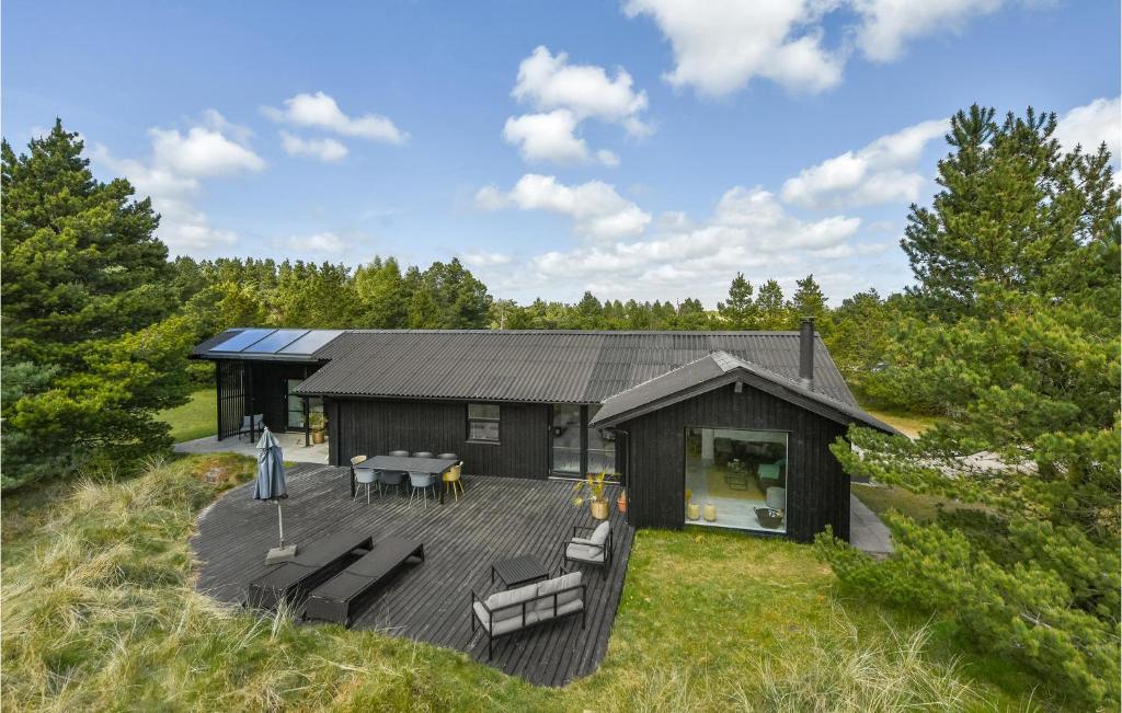 eine schwarze Hütte mit einem Deck im Gras in der Unterkunft Stunning Home In Blvand With Kitchen in Blåvand