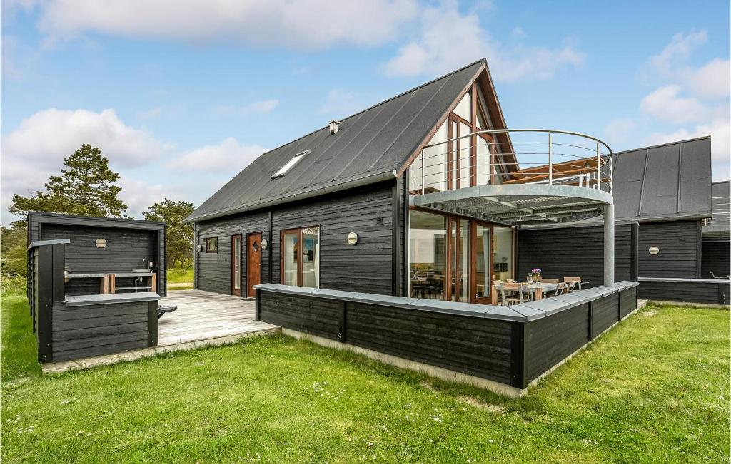 a black house with a deck on a lawn at Stunning Home In Rm With 3 Bedrooms, Sauna And Wifi in Rømø Kirkeby
