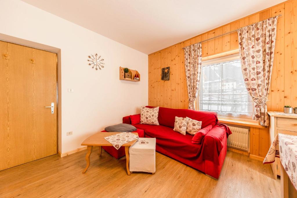 a living room with a red couch and a table at Casa Sara in Pozza di Fassa