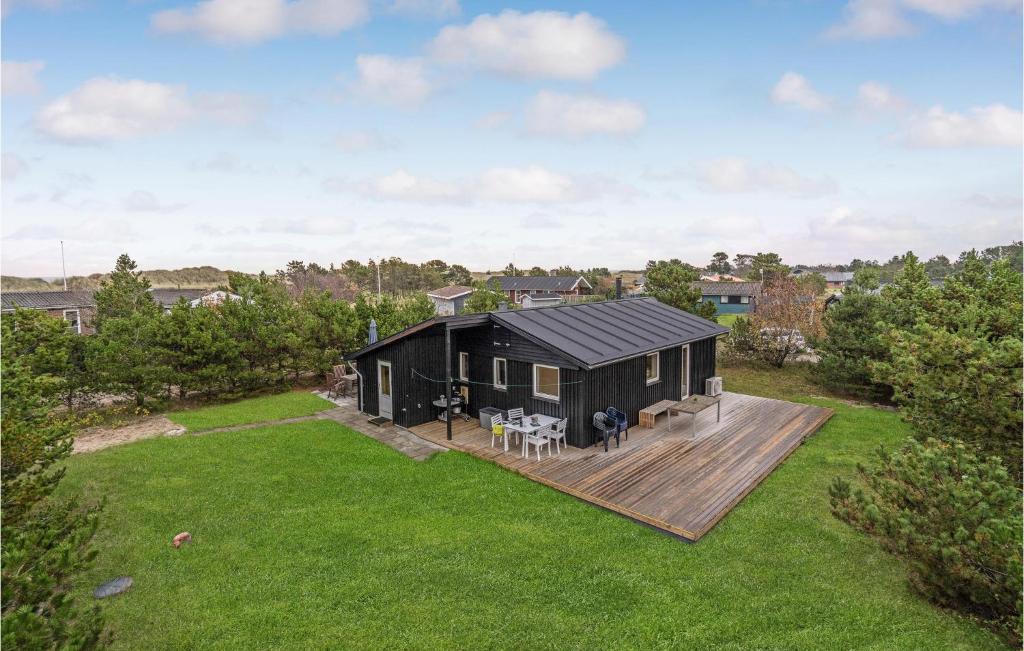 a black house on a wooden deck in a yard at Two-Bedroom Holiday Home In Saby in Sæby