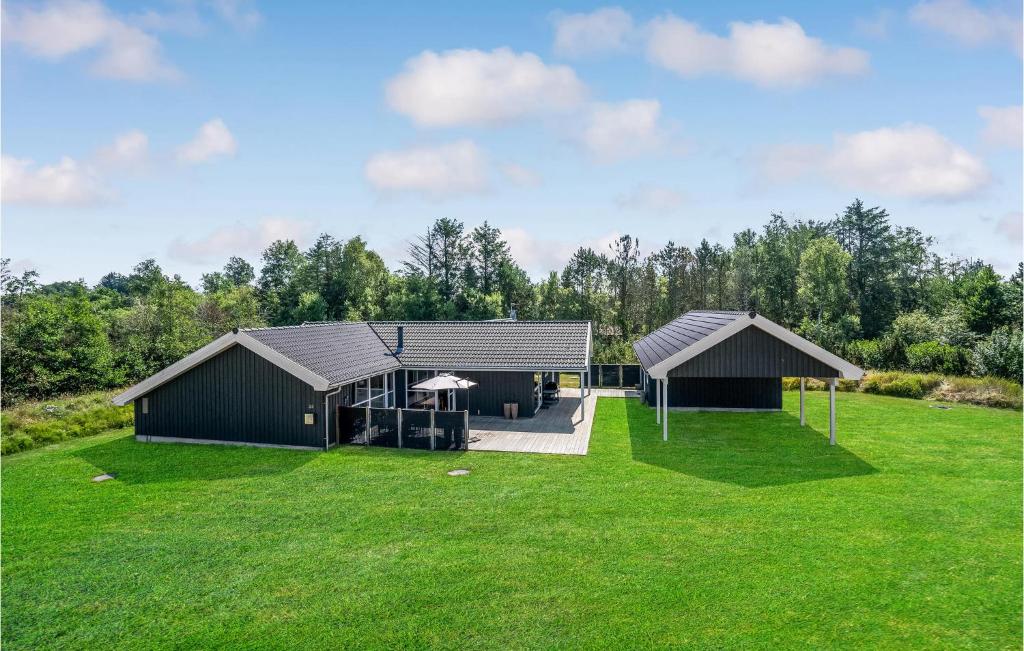 two black buildings on a green field with trees at Beautiful Home In Jerup With Sauna, Private Swimming Pool And Indoor Swimming Pool in Jerup