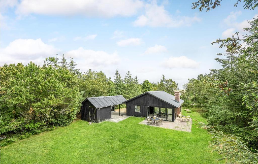 a small black house in the middle of a field at Amazing Home In lbk With 3 Bedrooms, Sauna And Wifi in Ålbæk