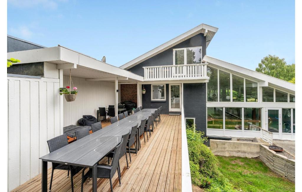 una casa con un ampio terrazzo con tavolo e sedie di Amazing Home In Roslev With 7 Bedrooms, Wifi And Indoor Swimming Pool a Glyngøre