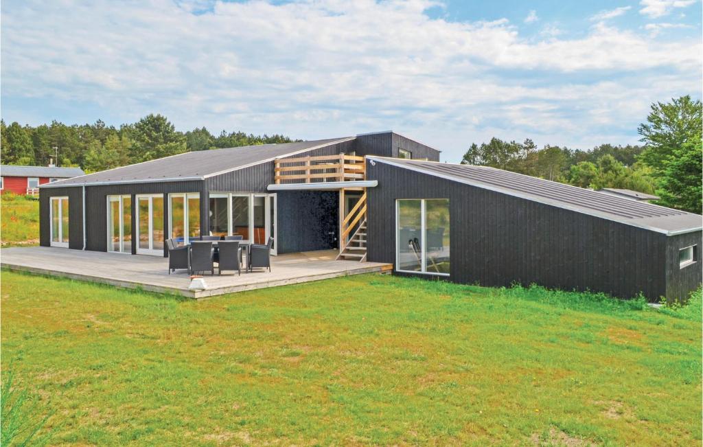 エーベルトフトにあるAmazing Home In Ebeltoft With Wifi, Private Swimming Pool And Indoor Swimming Poolの野原のデッキ付黒家