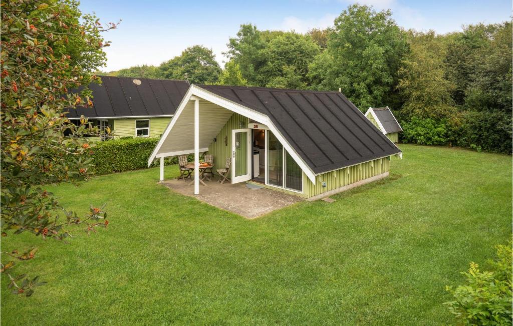 ein grünes Haus mit schwarzem Dach auf einem Hof in der Unterkunft Amazing Home In Grindsted With Kitchen in Grindsted