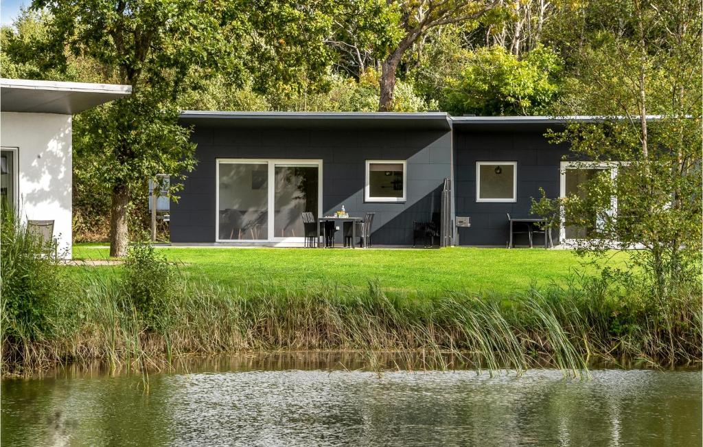 ein graues Haus mit einem Tisch auf einem Rasen neben einem See in der Unterkunft 3 Bedroom Awesome Home In Ringkbing in Ringkøbing