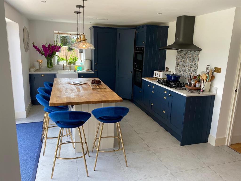 uma cozinha azul com uma mesa de madeira e bancos azuis em Modern family home central Cheltenham em Cheltenham