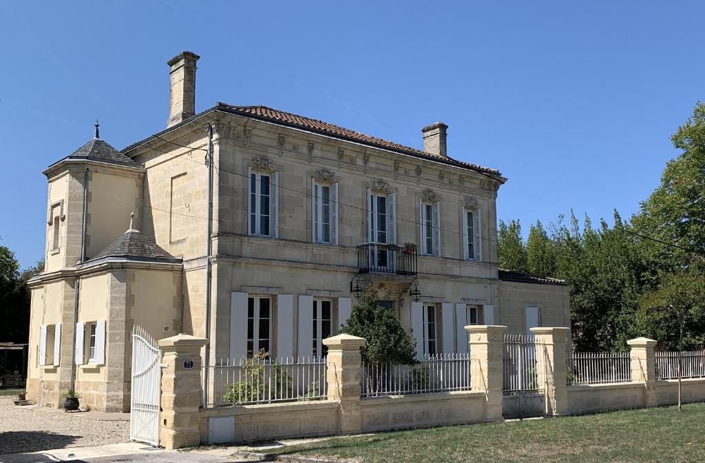 una casa vieja con una valla delante de ella en Suite privative Abella - Aile de maison bourgeoise, en Ambarès-et-Lagrave