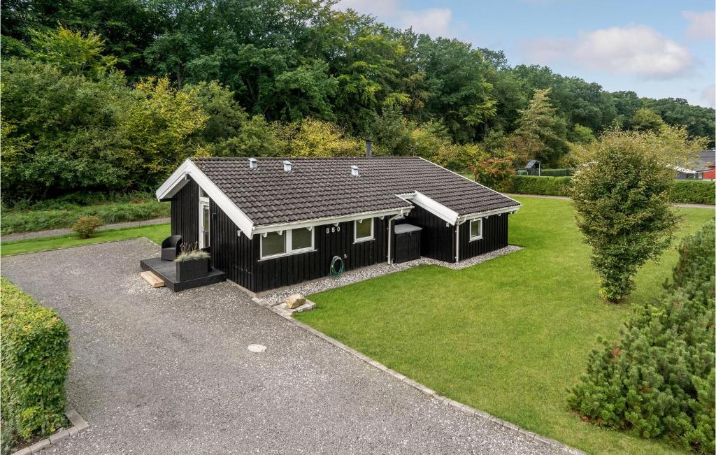 SønderbyにあるAmazing Home In Juelsminde With 3 Bedrooms, Sauna And Wifiの緑の芝生のある庭の黒い家