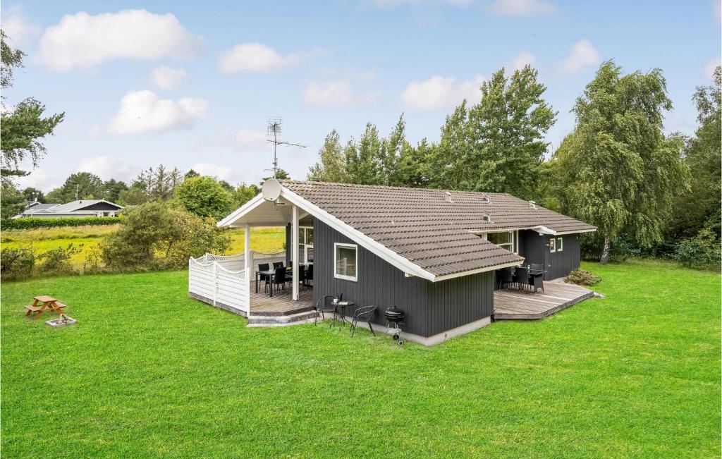 a small house in a yard with a green lawn at Holiday Home Mågelunden Rødby I in Kramnitse