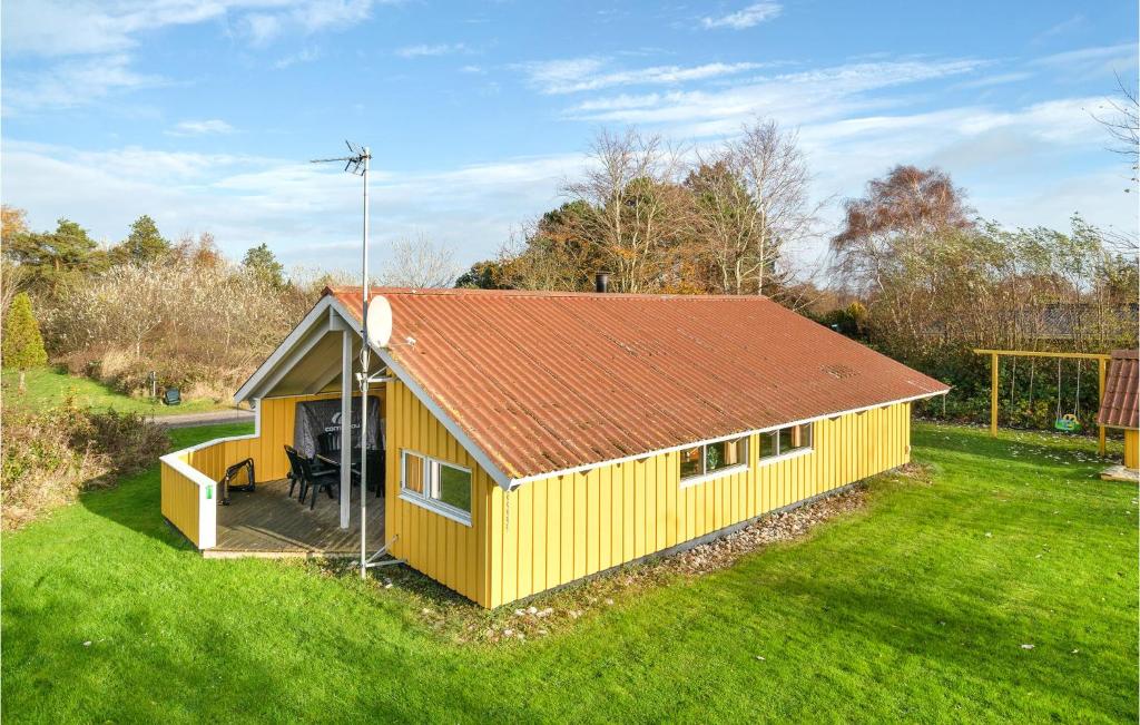 a yellow house with a red roof in a field at Holiday Home Spurvestræde in Dannemare