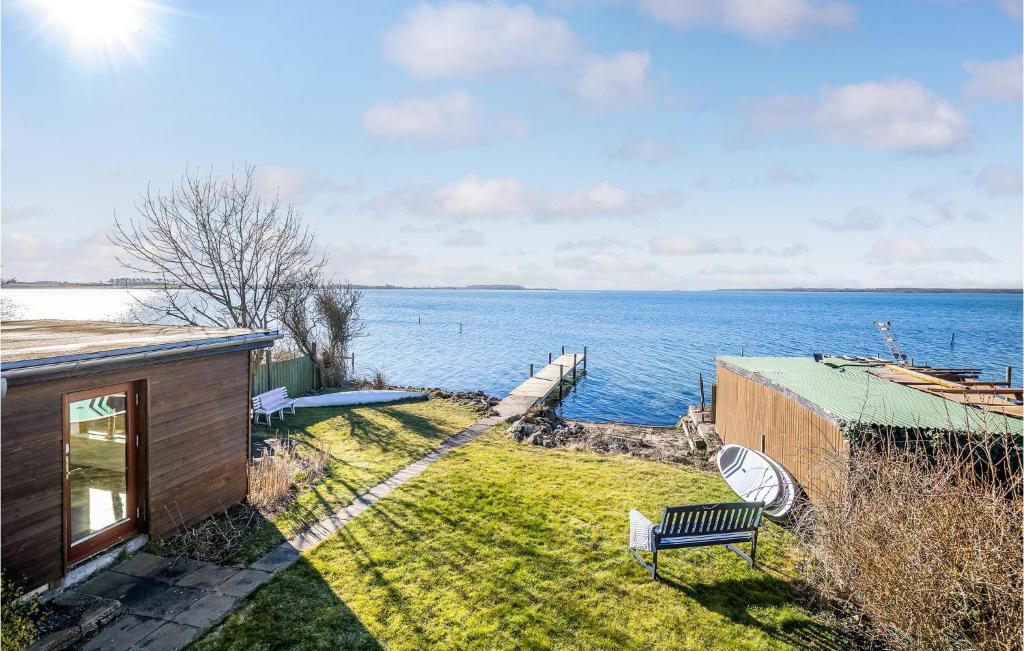 a bench sitting on the grass next to the water at Beach Front Home In Vggerlse With House Sea View in Væggerløse