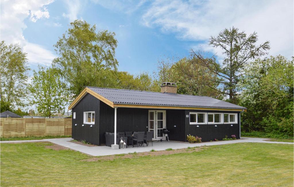 a black house with a patio in a yard at Amazing Home In Kge With Kitchen in Strøby Egede