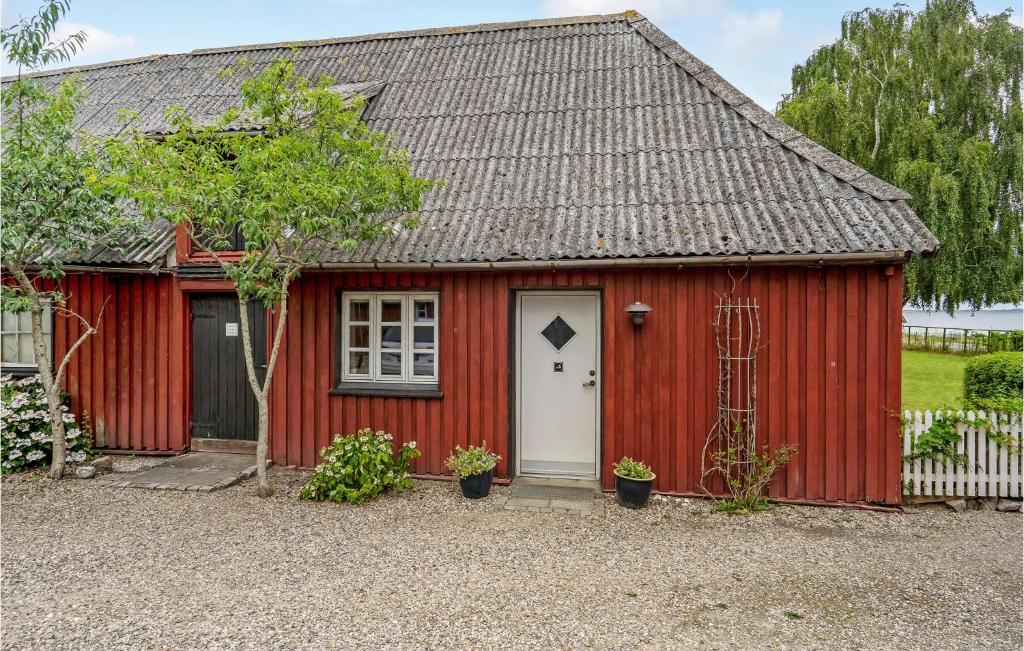 a red shed with a white door at Awesome Home In Skrup Fyn With House A Panoramic View in Skårupøre