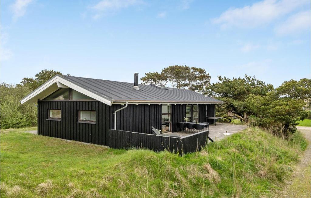 una casa nera in cima a una collina erbosa di Awesome Home In Fan With Wifi a Fanø