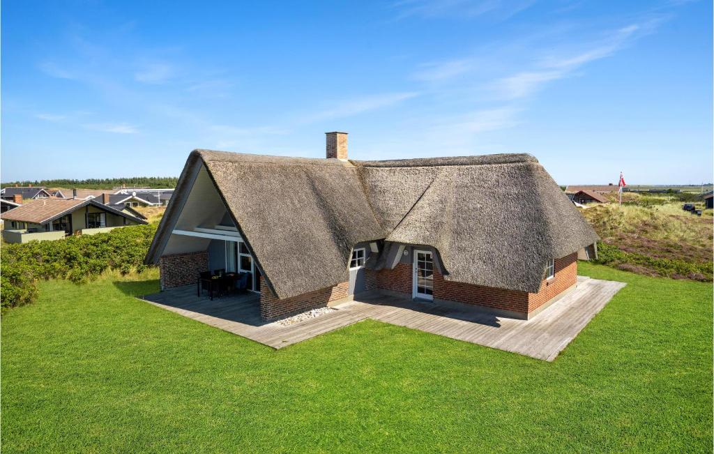a small house with a thatched roof on a lawn at Nice Home In Hvide Sande With Sauna in Bjerregård