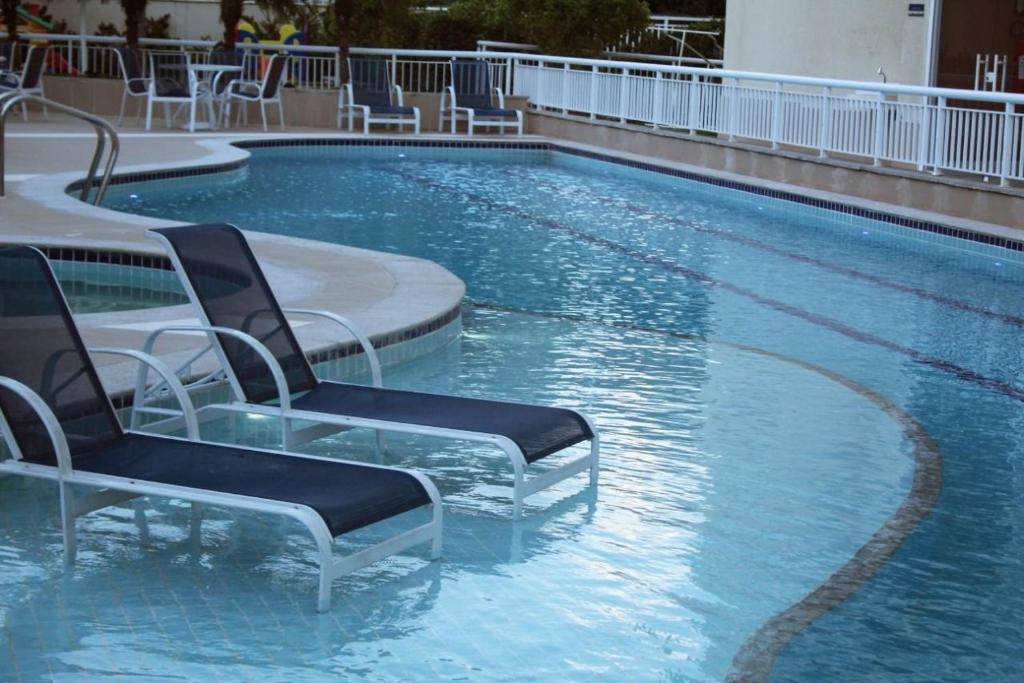 a swimming pool with two chairs in the water at RIOSTAY FLAT´s (RioCentro, Jeunesse Arena e Rock-in-Rio) in Rio de Janeiro