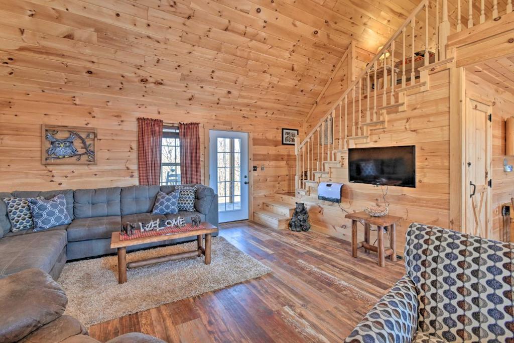 a living room with a couch and a tv in a log cabin at Quiet and Secluded Berea Cabin on 70-Acre Farm! in Berea
