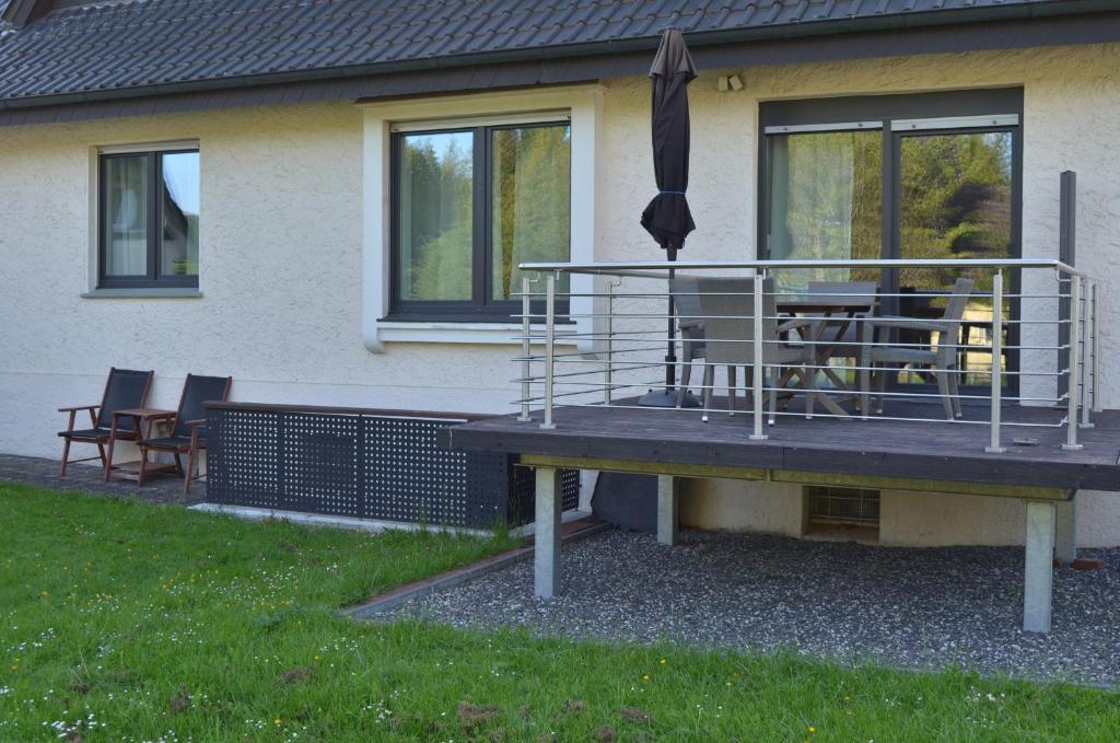 a deck with an umbrella and chairs on a house at Ferienwohnung Fam Wernicke in Preußisch Oldendorf