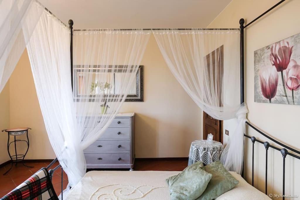 1 dormitorio con 1 cama con cortinas blancas y vestidor en Villa Malula a classy house in the countryside, en Capannori