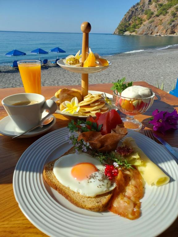 a breakfast plate with an egg on a table near the beach at Agia Roumeli Hotel in Agia Roumeli