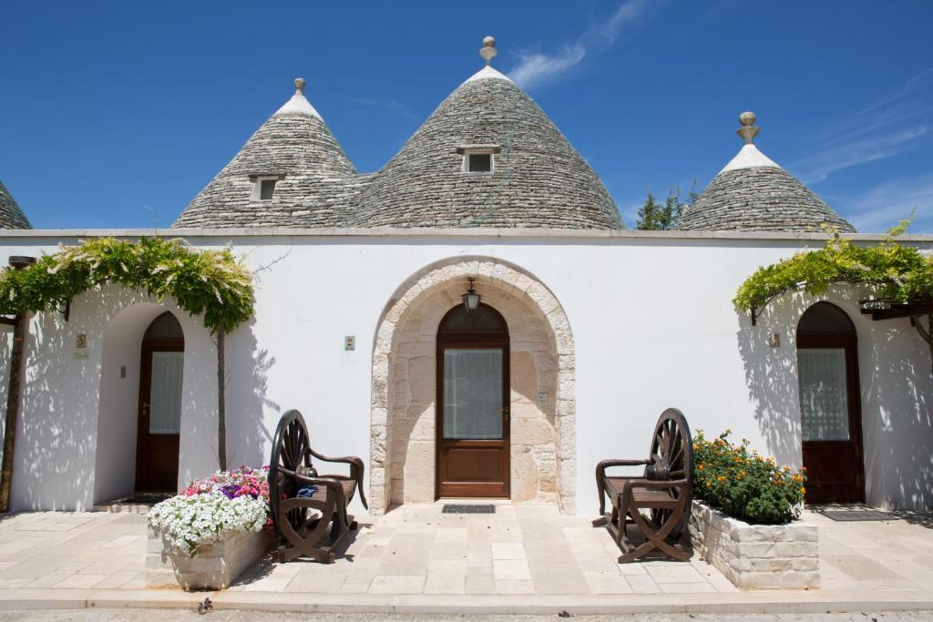 um edifício branco com duas cadeiras e flores à frente em Bed and Breakfast Trulli San Leonardo em Alberobello