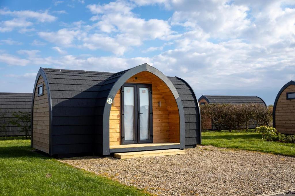 a small shed with a window in the grass at Camping Pods Silver Sands Holiday Park in Lossiemouth