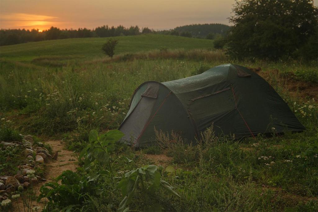 une tente dans un champ avec le coucher du soleil en arrière-plan dans l'établissement Rent a tent - Namiot w Praekologicznym gospodarstwie, à Pozezdrze