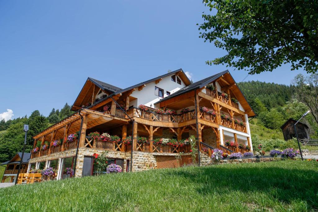 una grande casa in legno con balconi e fiori di Conacul Baciu a Fundu Moldovei