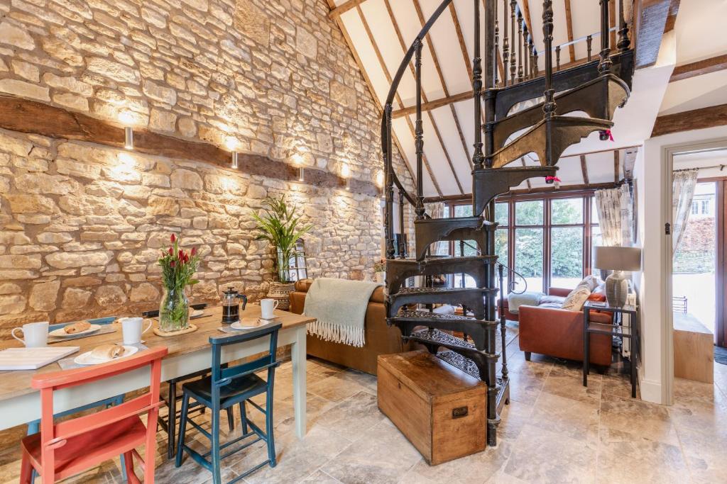 a spiral staircase in a living room with a stone wall at Otters Abode in Blockley