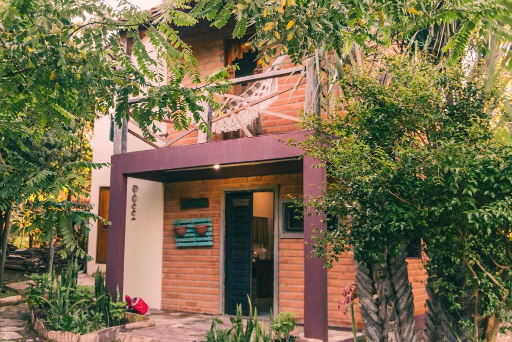 a house with a purple front door and trees at Recanto Pitanga in Vale do Capao