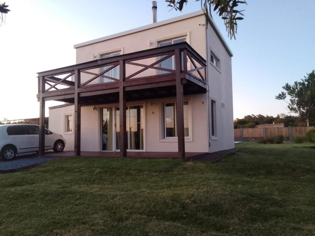 uma casa branca com um carro estacionado em frente dela em La Quijotada em Punta Colorada