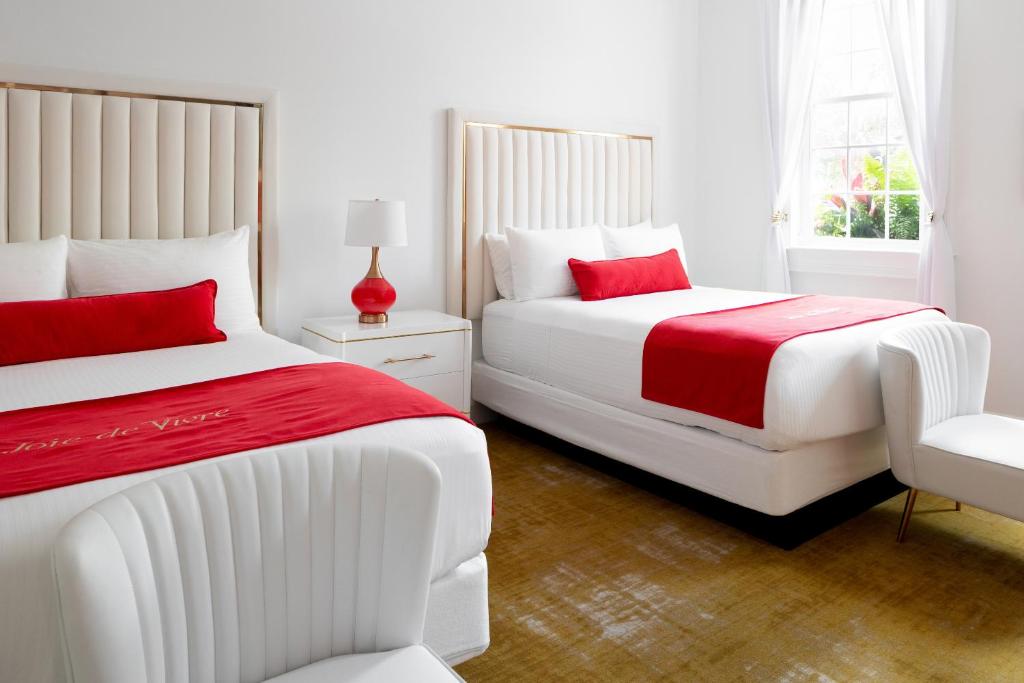 a white bedroom with two beds and a chair at The Vendue, Downtown Art Hotel in Charleston
