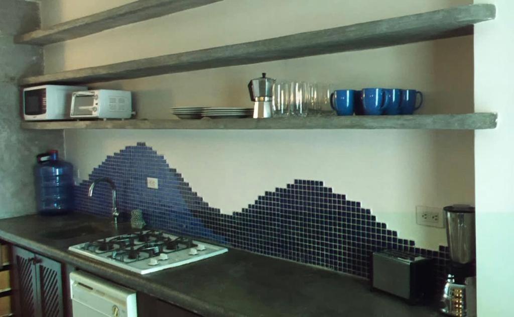 Il dispose d'une cuisine avec une cuisinière et un mur en carrelage noir. dans l'établissement Bahia Dorada 1 habitación, à Pampatar