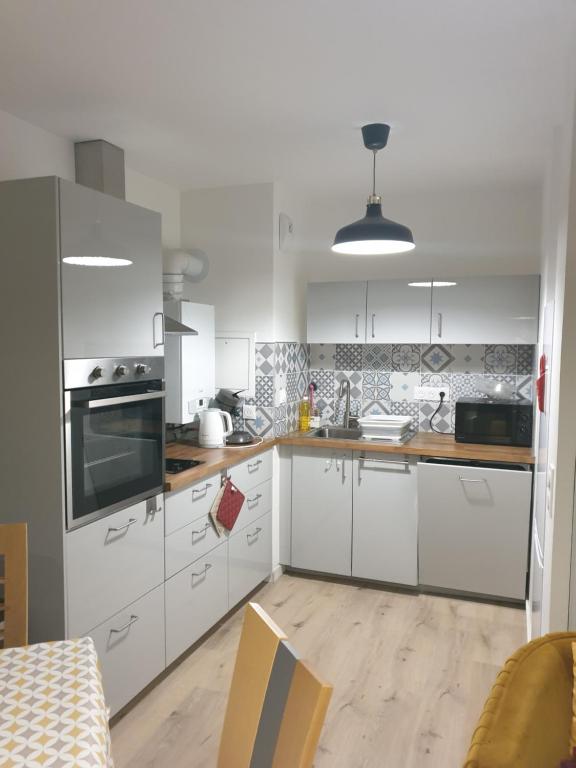 a kitchen with white cabinets and a stove top oven at Confortable T2 NEUF - RDC - 2/4 personnes in Mondeville