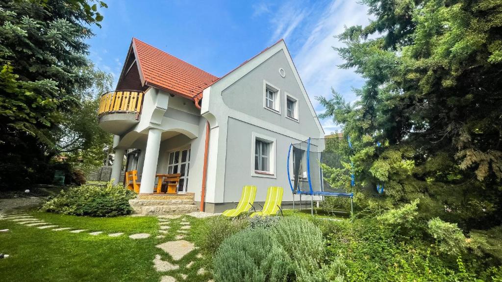 ein kleines Haus mit gelben Stühlen im Hof in der Unterkunft Nyírfa Vendégház in Csopak