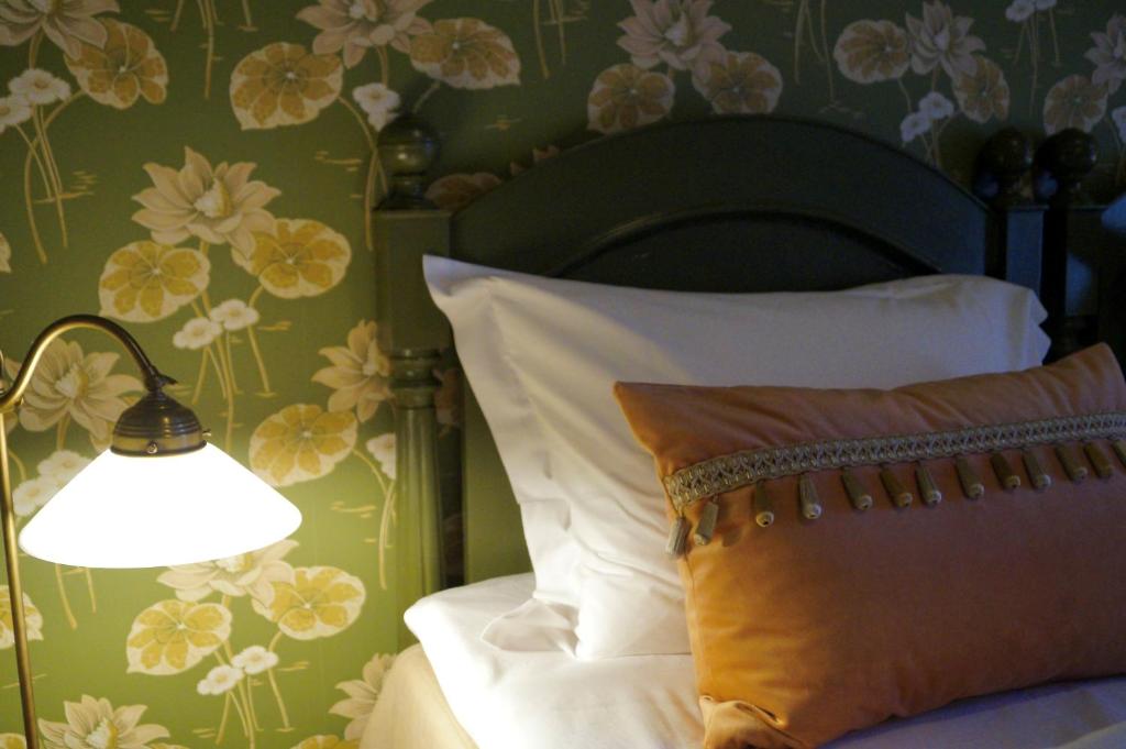 a bed with a pillow and a lamp with a flower wallpaper at Jugend 1905 in Ålesund