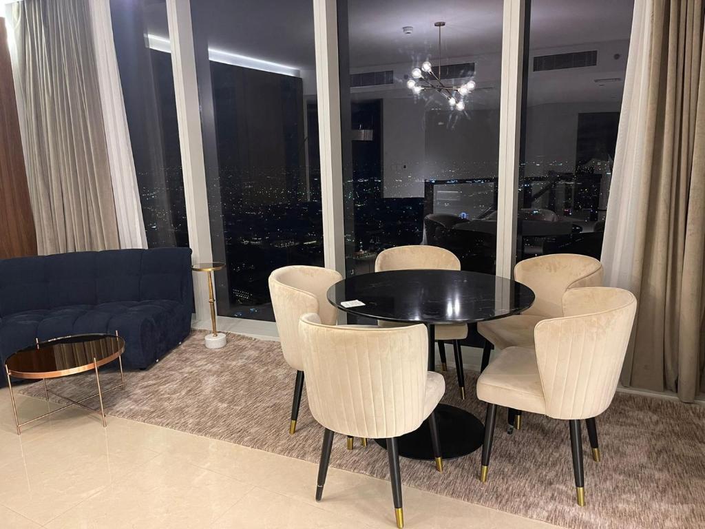een woonkamer met een tafel en stoelen en een bank bij Raffal Tower Apartment in Riyad