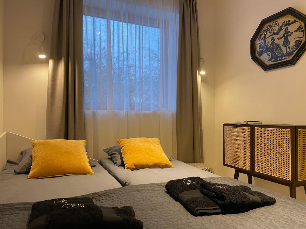 um quarto com 2 camas com almofadas amarelas e uma janela em Fotel Dunakanyar em Nagymaros